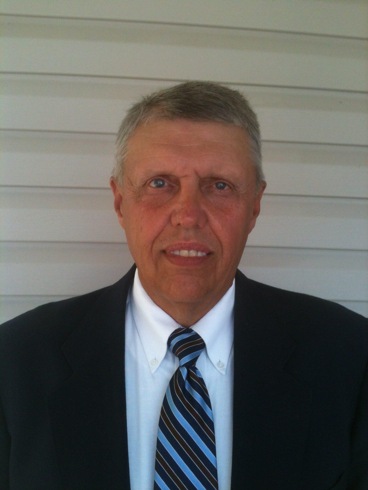 Larry Woods smiles at the camera, and he is seen wearing a blue and black tie